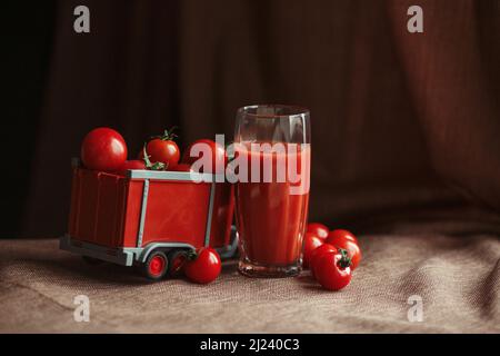 Tomaten in einem Spielzeuganhänger Tomatensaft in einem Glas Stockfoto