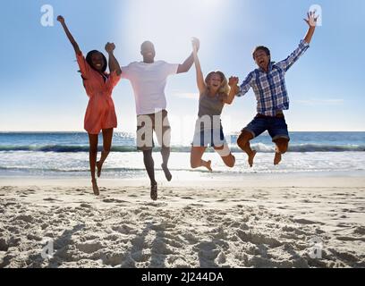 Es ist Sommerzeit. Zwei junge Paare, die am Strand springen und Spaß haben. Stockfoto