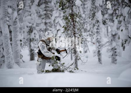 Ein Kampfkontrolleur mit der Kentucky Air National Guard's 123. Special Tactics Squadron schneidet, die wegen eines Feuers in Grubbbnäudden, Schweden, am 11. Januar 2022 entzündet wurde. 15 Mitglieder der STS von 123. – darunter Kampfkontrolleure; Paraskuemen; Spezialaufklärer; Durchsuchung, Ausweichmanöver, Widerstands- und Fluchttruppen sowie Unterstützung von Airmen – kamen hierher, um ihre Beziehung zu europäischen Partnern während eines Schulungskurses zum arktischen Krieg auszubauen. (USA Foto der Air National Guard von Phil Speck) Stockfoto