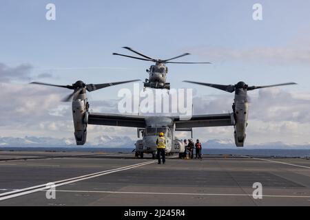 Ein britischer Hubschrauber der Royal Navy Merlin Mk2 hebt ab, als ein US Marine Corps MV-22B Osprey während der Übung Cold Response 2022, Norwegisches Meer, 26. März 2022 auf der HMS Prince of Wales betankt wird. Die Osprey ist Marine Medium Tiltrotor Squadron 261, 2D Marine Aircraft Wing zugeordnet. Übung Cold Response ’22 ist eine alle zwei Jahre stattfindende Übung in ganz Norwegen, an der jeder seiner Militärdienste sowie 26 weitere mit der Organisation des Nordatlantikvertrags verbundene Nationen und regionale Partner teilnehmen. (USA Marine Corps Foto von Lance CPL. Elias E. Pimentel III) Stockfoto