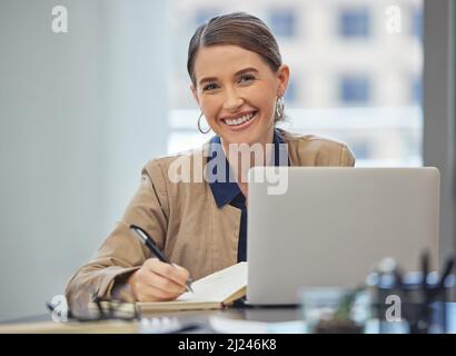 Ich habe einen gebucht, keine Sorge. Aufnahme einer attraktiven jungen Geschäftsfrau, die allein in ihrem Büro sitzt und Notizen schreibt. Stockfoto