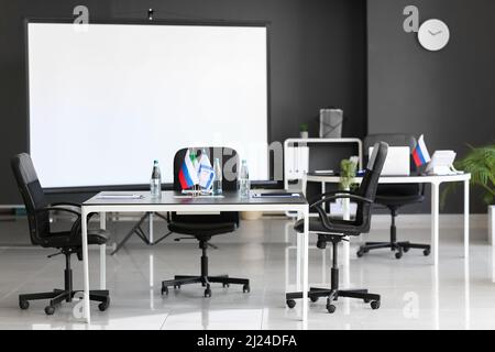 Innenraum des Konferenzraums mit italienischen, israelischen und russischen Flaggen auf dem Tisch Stockfoto