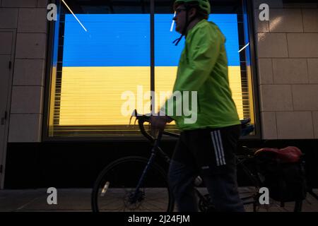 Seattle, USA. 29. März 2022. Die Nordstoms Ukraine Flagge als ein Radfahrer passiert. Stockfoto