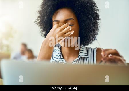 Es war ein langer Tag und er fühlt es. Eine kurze Aufnahme einer jungen Designerin, die in einem modernen Büro Kopfschmerzen hat. Stockfoto
