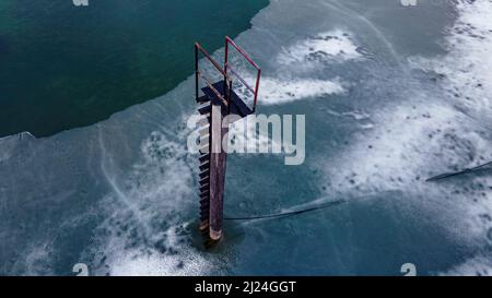 Um diese rohe Tauchplattform auf einem Teich herum sind Holzdutenspuren verstreut Stockfoto