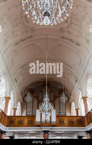 Symmetrische Ansicht auf Orgelpfeife und Kronleuchter der St. Peter Kirche in Zürich Stockfoto