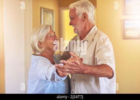 Sie tanzten jeden Tanz zusammen vom ersten Tag an. Aufnahme eines glücklichen älteren Paares, das zu Hause tanzt. Stockfoto