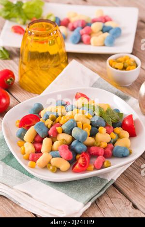 Farbige Gnocchi mit Gemüse und süßem Mais. Stockfoto