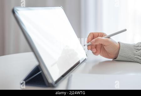 Nahaufnahme einer Frau, die mit einem Stift und einem digitalen Tablet-pc arbeitet. Frau, die mit einem Stift auf einem Tablet zeichnet. Eine kurze Aufnahme einer Frau, die im Wohnzimmer sitzt und sie benutzt Stockfoto