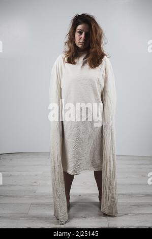 Nahaufnahme Porträt einer verrückten Frau in Zwangsjacke auf weißem Hintergrund. Monochrom. Stockfoto