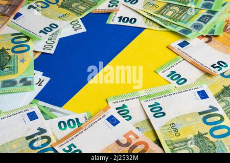 Lot von Papier 150 Euro-Banknoten auf ukrainischer Flagge. Draufsicht. Geldhilfe-Konzept Stockfoto