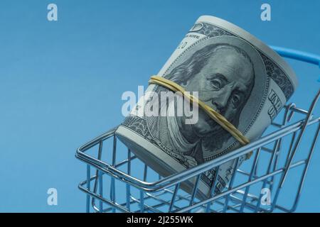 In einen Schlauch gerollte Dollars liegen in einem Einkaufskorb. Stockfoto