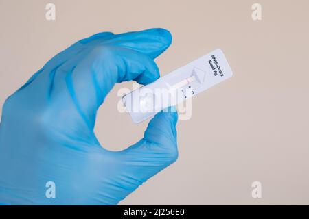 Negativer Covid-19 / SARS-CoV-2 Schnellantigen-Test, der während der Corona-Pandemie in medizinischen blauen Handschuhen vor weißem Hintergrund durchgeführt wurde Stockfoto