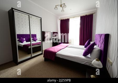 Gemütliches Schlafzimmer im Hotelzimmer, klassisches Schlafzimmer im heimischen Stil, Bettwäsche in sanften Farbtönen. Stockfoto