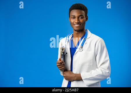 Selbstbewusster schwarzer Arzt posiert über blauem Studiohintergrund. Stockfoto