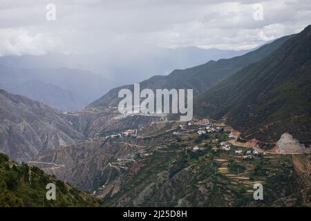 Spektakuläre Landschaft mit Hügeln, Tälern und tibetischer Stadt auf einem Hügel in Yunnan Stockfoto