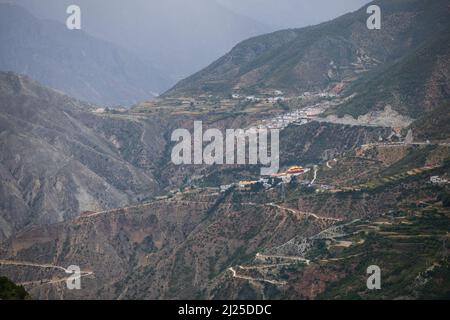 Spektakuläre Landschaft mit Hügeln, Tälern und tibetischer Stadt auf einem Hügel in Yunnan Stockfoto