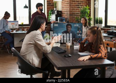 Geschäftsfrau im Gespräch mit afroamerikanischer Projektmanagerin über neue Partnerschaften. Mitarbeiter des Finanzunternehmens kommuniziert mit dem CEO frische Marketingstrategien und -Ideen. Stockfoto