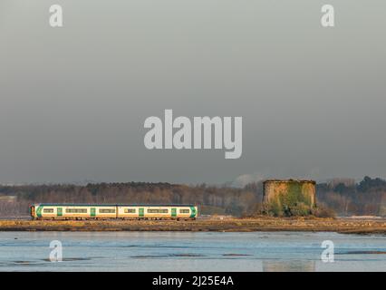 Fota Island, Cork, Irland. 30.. März 2022. Eine Stadt, die am frühen Morgen mit einem Pendlerzug verbunden ist, der an einem Martello Tower auf Fota Island, Co. Cork, Irland, vorbeifährt. - Credit; David Creedon / Alamy Live News Stockfoto