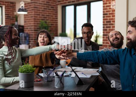 Begeisterte, erfolgreiche, multirassische Geschäftsleute, die bei einem Marketing-Meeting im Startup-Office ihre Geschäftserfolge genießen konnten. Vielfältiges Team, das am Umsatz des Unternehmens arbeitet Stockfoto