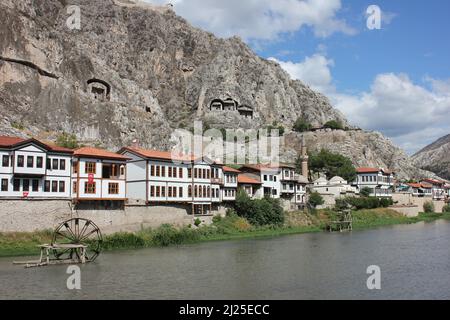 Alte Steingräber von Königen auf den Hügeln und traditionelle alte Holzhäuser. Historisches Dorf am Fluss und eine Wassermühle Rad im Wasser Stockfoto