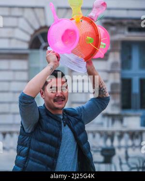 London UK 30 March 2022 der philippinische Künstler Leeroy New, mit seinem Helm aus recycelten Gegenständen, der noch bis zum 26. April anlässlich des Earth Day zu sehen sein wird. Es handelt sich um die erste britische Installation von New, die in Form von drei fantastischen, hochgedrehten Schiffen, die aus Plastikabfällen und recycelten Materialien gebaut wurden, in einem Höhenmeter vom Boden entfernt entsteht. Die Installation greift die Kultur und Mythologien der Heimat des Künstlers auf den Philippinen auf, einem Land an der vordersten Front der Klimanotlage. Paul Quezada-Neiman/Alamy Live News Stockfoto