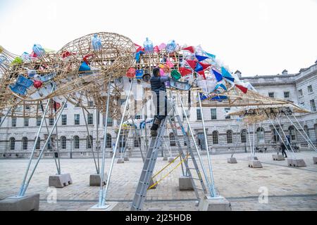 London UK 30 March 2022 der philippinische Künstler Leeroy New nimmt die letzten Anpassungen an seiner Installation vor, die noch bis zum 26. April anlässlich des Earth Day zu sehen sein wird. Es handelt sich um die erste britische Installation von New, die in Form von drei fantastischen, hochgedrehten Schiffen, die aus Plastikabfällen und recycelten Materialien gebaut wurden, in einem Höhenmeter vom Boden entfernt entsteht. Die Installation greift die Kultur und Mythologien der Heimat des Künstlers auf den Philippinen auf, einem Land an der vordersten Front der Klimanotlage. Paul Quezada-Neiman/Alamy Live News Stockfoto