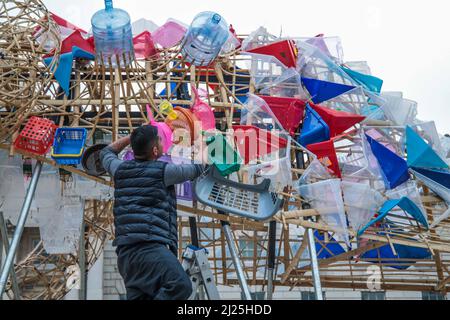 London UK 30 March 2022 der philippinische Künstler Leeroy New nimmt die letzten Anpassungen an seiner Installation vor, die noch bis zum 26. April anlässlich des Earth Day zu sehen sein wird. Es handelt sich um die erste britische Installation von New, die in Form von drei fantastischen, hochgedrehten Schiffen, die aus Plastikabfällen und recycelten Materialien gebaut wurden, in einem Höhenmeter vom Boden entfernt entsteht. Die Installation greift die Kultur und Mythologien der Heimat des Künstlers auf den Philippinen auf, einem Land an der vordersten Front der Klimanotlage. Paul Quezada-Neiman/Alamy Live News Stockfoto