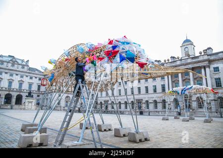 London UK 30 March 2022 der philippinische Künstler Leeroy New nimmt die letzten Anpassungen an seiner Installation vor, die noch bis zum 26. April anlässlich des Earth Day zu sehen sein wird. Es handelt sich um die erste britische Installation von New, die in Form von drei fantastischen, hochgedrehten Schiffen, die aus Plastikabfällen und recycelten Materialien gebaut wurden, in einem Höhenmeter vom Boden entfernt entsteht. Die Installation greift die Kultur und Mythologien der Heimat des Künstlers auf den Philippinen auf, einem Land an der vordersten Front der Klimanotlage. Paul Quezada-Neiman/Alamy Live News Stockfoto