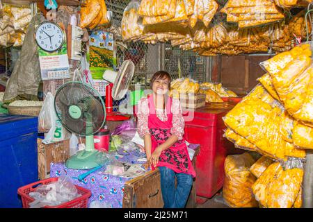 Bangkok, Thailand - 12. Mai 2009: Eine nicht identifizierte lächelnde Frau sitzt auf der Straße auf dem Blumenmarkt am Morgen und verkauft Blumen bei Pak Klong Thalat. Stockfoto