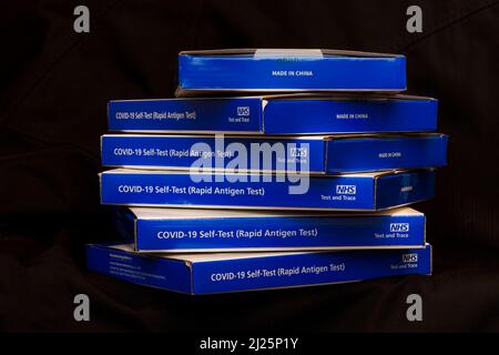 Blaue NHS Covid-19-Testkits für lateralen Fluss/Coronavrus-Testkits für schnelles laterales Flussantigen vor schwarzem Hintergrund Stockfoto