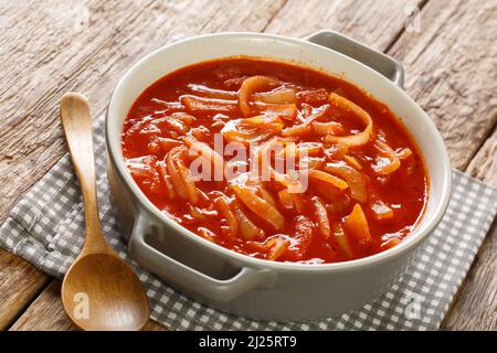 Köstlicher Zwiebeleintopf mit Tomaten, Knoblauch und Gewürzen aus der Nähe in einem Topf auf dem Tisch. Horizontal Stockfoto