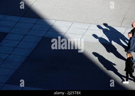 Schatten und Silhouetten von Menschen auf dem Pflastersteinpflaster. Stockfoto