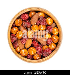 Knusprige Mischung, in einer Holzschüssel. Knusprige Mischung aus gesalzenen Brezelbällchen, gerösteten Mandeln und gebackenen Preiselbeeren. Nahaufnahme von oben. Stockfoto