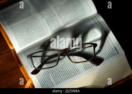 Öffne die bibel mit einer Brille. Kirche Kerzen in der Kirche. Frau, die die Jungfrau betet. Stockfoto