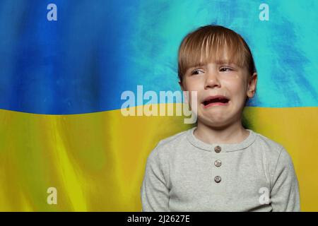 Weinendes Kind Mädchen vor ukrainischer Flagge Hintergrund. Beenden Sie den Krieg in der Ukraine Stockfoto