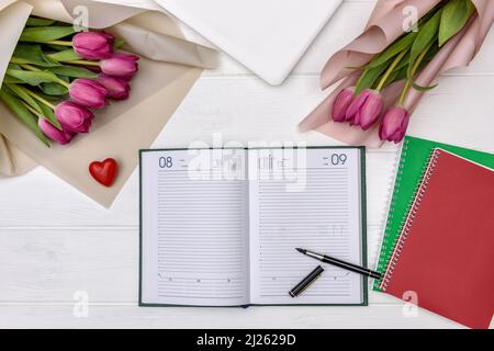 Leerer Notizblock mit Tulpen auf Holztisch Stockfoto