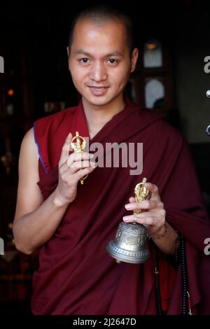 Kloster Pema Osel Ling. Buddhistischer Mönch in einem Lama-Kleid. Der Mönch hält die rituellen Attribute Buddhismus, Rosenkranz, Vajra, Glocke. Stockfoto