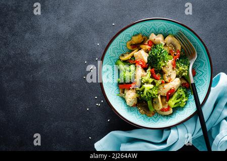 Hähnchen unter Rühren mit Gemüse und Pilzen braten. Draufsicht Stockfoto