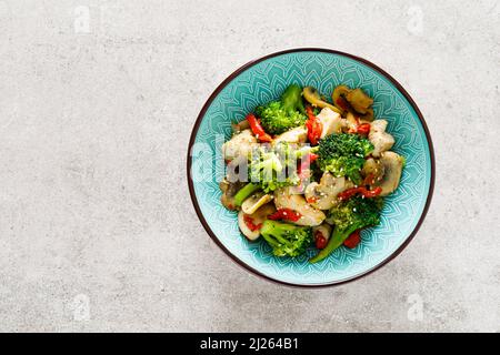 Hähnchen unter Rühren mit Gemüse und Pilzen braten. Draufsicht Stockfoto