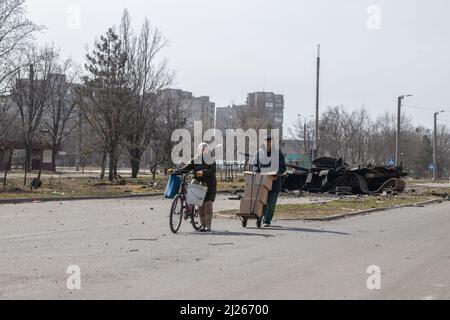 Ein Paar rollte russische humanitäre Hilfe an einem zerstörten Panzer im Zentrum von Mariupol vorbei. Der Kampf zwischen den russischen / pro-russischen Truppen und den vom Asow-Bataillon angeführten, abtrünnenden ukrainischen Kräften geht in der Hafenstadt Mariupol weiter. (Foto von Maximilian Clarke / SOPA Images/Sipa USA) Stockfoto