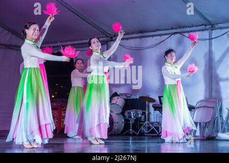 Asiatische Tänzerinnen auf der Bühne während der Festlichkeiten im Herbst. Sie führen einen traditionellen Tanz mit dem Titel „Floral Essence“ auf Stockfoto