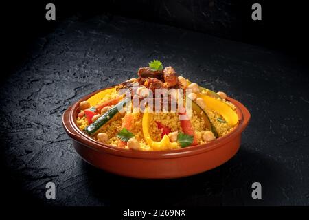 Fleisch- und Gemüsecouscous, festliche arabische Speisen mit Kichererbsen, auf dunklem Hintergrund Stockfoto