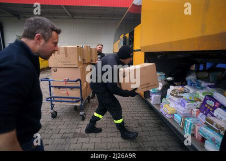 Ein Wachmann lädt Hilfsgüter in einen Bus in Przemysl ein, der dem britischen Freiwilligen Cliff Wilson (links) gehört und ihn in die Ukraine transportieren und bei seiner Rückkehr ukrainische Frauen und Kinder abholen und sie über die Grenze in die Sicherheit in Polen zurückbringen wird. Bilddatum: Mittwoch, 30. März 2022. Stockfoto