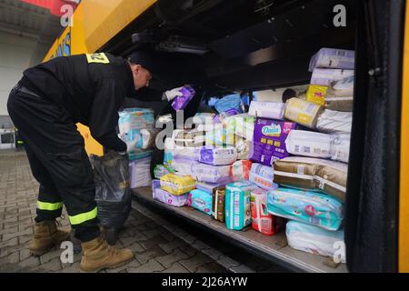 Ein Wachmann verlädt Hilfsgüter in einen Bus des britischen Freiwilligen Cliff Wilson, der ihn vom polnischen Przemysl in die Ukraine transportieren und bei seiner Rückkehr ukrainische Frauen und Kinder abholen und über die Grenze in die Sicherheit in Polen zurückbringen wird. Bilddatum: Mittwoch, 30. März 2022. Stockfoto