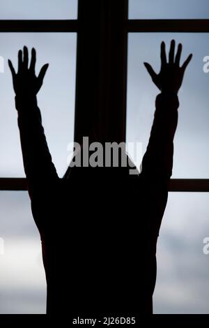 Silhouette einer Frau, die aus dem Fenster schaut. Stockfoto