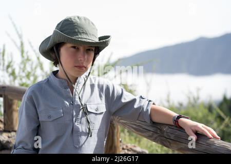 Ein trauriger Teenager steht auf einer Aussichtsplattform hoch in den Bergen. Stockfoto