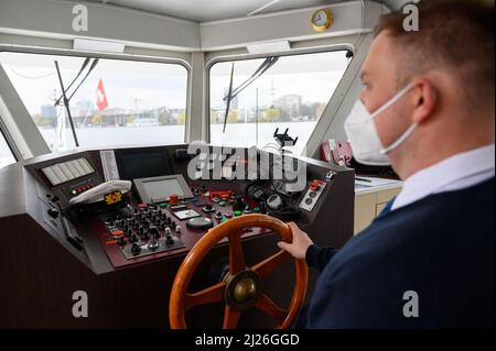 30. März 2022, Hamburg: Schiffmeister Nils Lübeck steuert den Alster-Dampfschiff „Alsterwasser“ über die Außenalster. Nach schweren Einschränkungen durch die Corona-Pandemie startet die „Weiße Flotte“ auf der Hamburger Alster am Freitag mit einem vollen Programm wieder in die neue Saison. Darüber hinaus wurde laut ATG Alster-Touristik die Finanzierungszusage für die Elektrifizierung der ersten Schiffe bewilligt. Foto: Jonas Walzberg/dpa Stockfoto