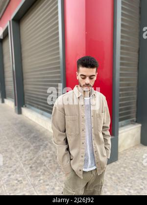 Attraktives Modell für junge Männer in grauer Weste und grauer, kurz stehender Garage gegenüber Stockfoto