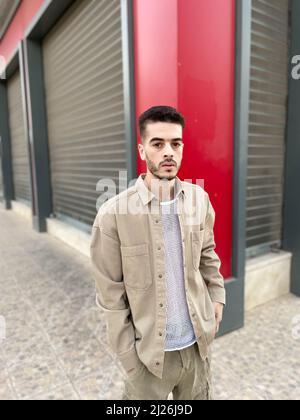 Attraktives Modell für junge Männer in grauer Weste und grauer, kurz stehender Garage gegenüber Stockfoto
